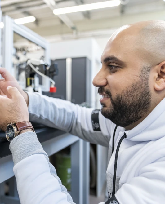 Student interacting with a conveyor automation system, ensuring robotic arms accurately sort coloured blocks in a training lab Student interacting with a conveyor automation system, ensuring robotic arms accurately sort coloured blocks in a training lab